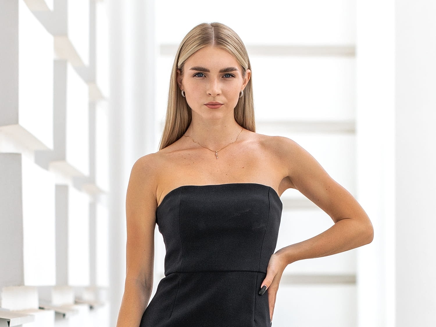 Model in a black strapless dress posing confidently.