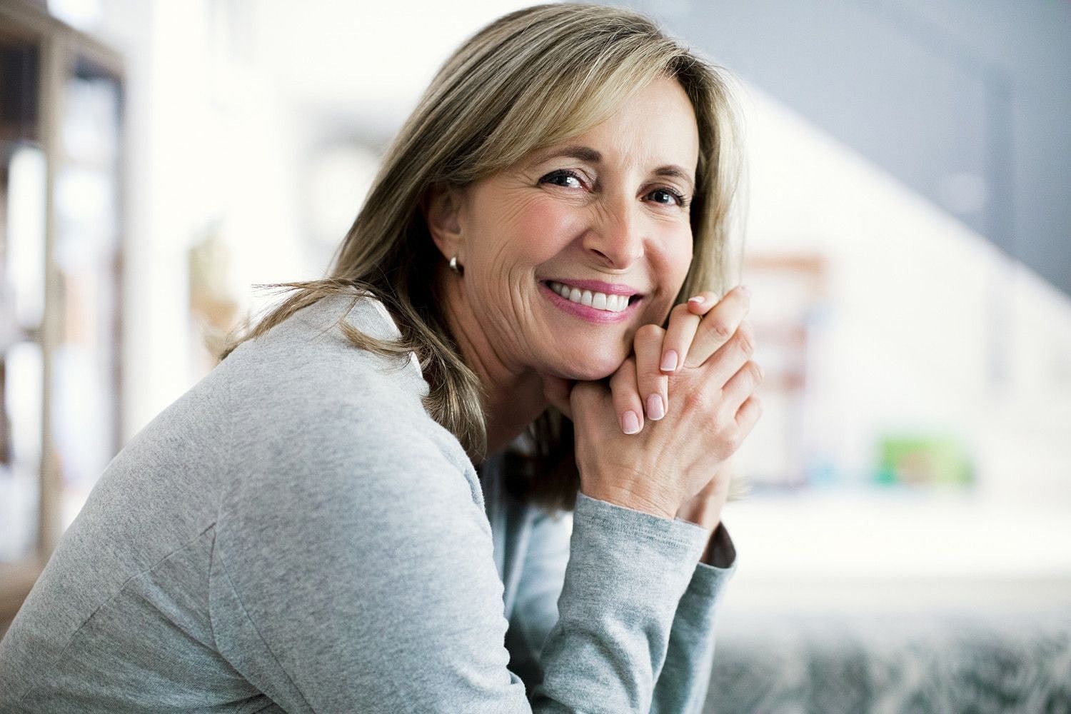 Smiling woman with hands clasped in relaxation.