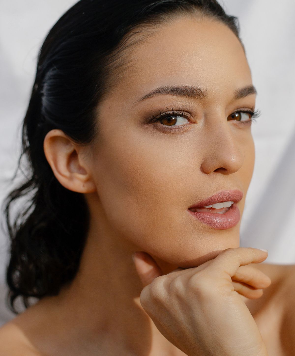Close-up of woman with soft makeup and smile.